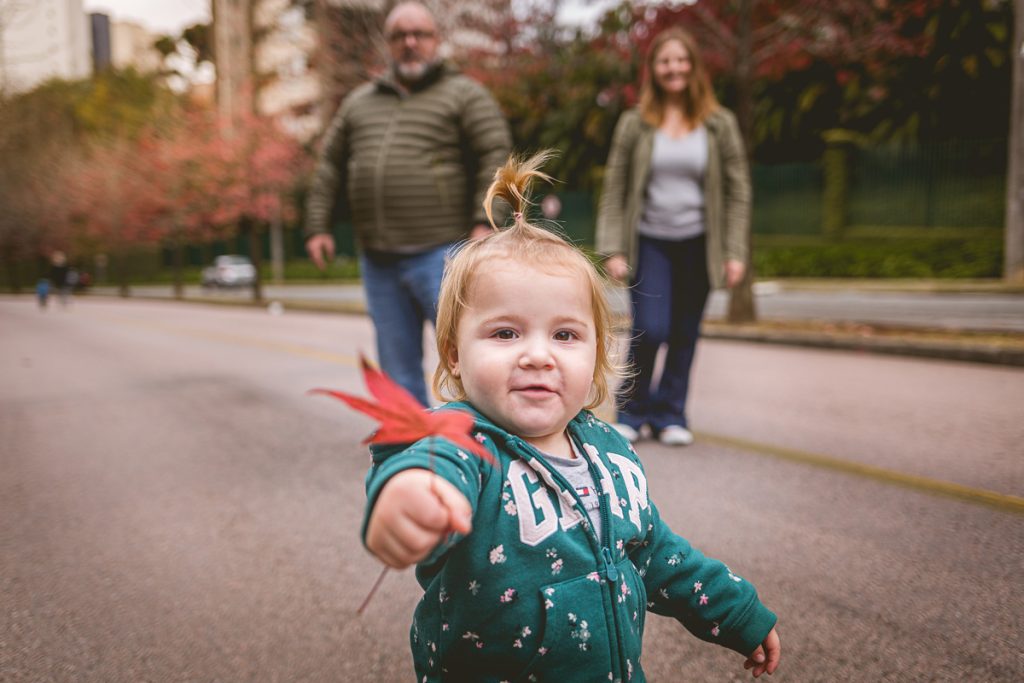 Ensaio de família em Curitiba na Rua do Outono - criança brincando com as folhas de plátano