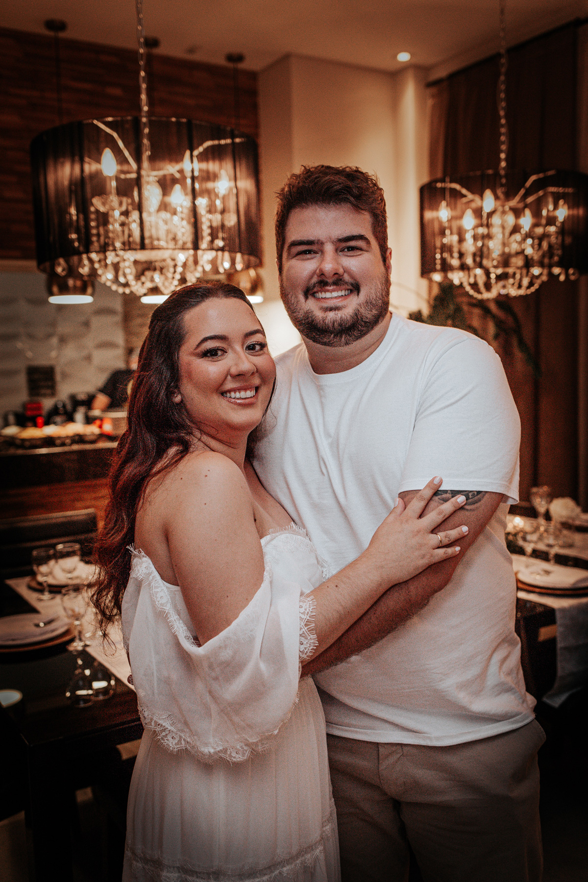 Casal Ana e Luiz sorrindo em jantar de noivado intimista; fotografia de momentos reais em Curitiba.