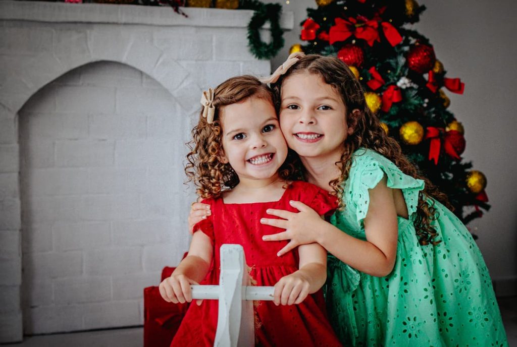 irmãs pequenas juntinhas sorrindo lindamente durante ensaio de Natal em Curitiba